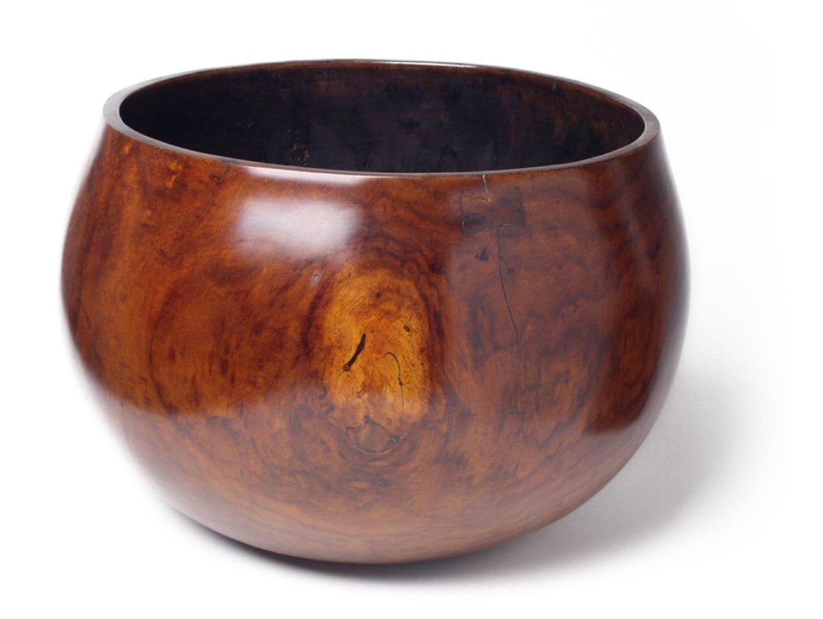 This bowl was hewn by hand from Kou, a prized wood that has become very scarce in Hawaii. It does not consist of any design, just the grain of the dark wood.